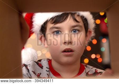 The Surprise Of Emotion In A Boy In A New Years Jumper And A Hat Of Santa Clau