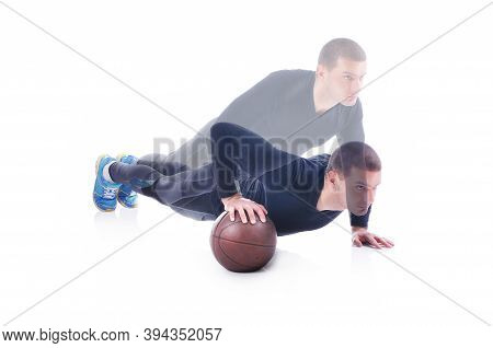 Concentrated Young Sportsman Exercising And Doing Push Ups On The Basketball. White Background. Stud