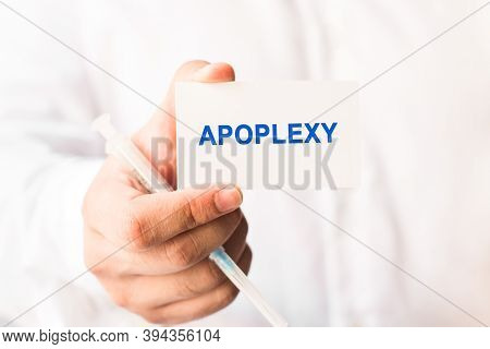 Word Apoplexy On A White Background With A Syringe In Hand. Medicine Concept