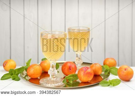 Delicious Plum Liquor, Ripe Fruits And Mint On Table Against White Background. Homemade Strong Alcoh