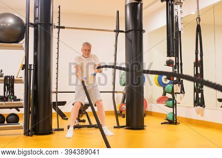Marure Man In Sportswear Pulling The Ropes In Gym