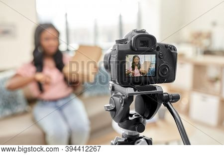 blogging, videoblog and people concept - displeased african american female video blogger with parcel box and camera videoblogging at home