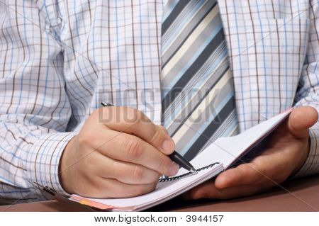 Primo piano di mano di una Businessman\ con una penna per scrivere qualcosa.