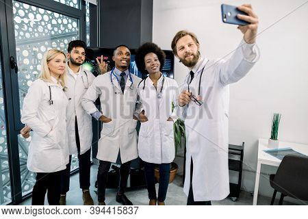 Happy Smiling Team Of Multiethnical Five Doctors, African, Caucasian And Indian, Standing At The Mod