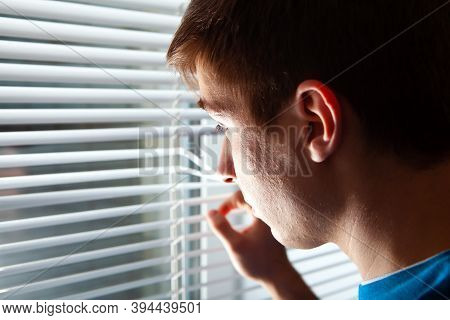 Young Man Next To Jalousie In A Room