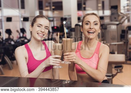 Mother And Daughter Drinking Protein Shakes At Gym. They Look Happy, Fashionable And Fit.