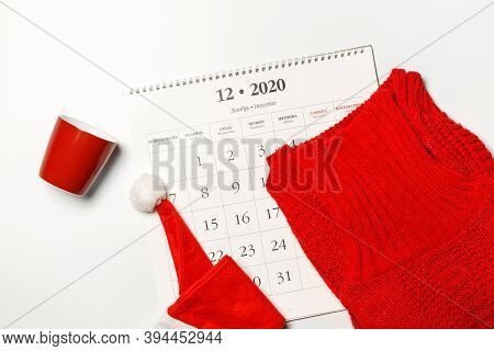 Calendar Page For December 2020, Red Sweater, Cup And Santa Hat On Top. On A White Background, Horiz