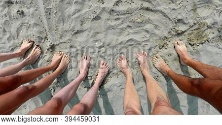 Line Of Ten Feet Of A Family Of Five On The Sand By The Sea In Summer