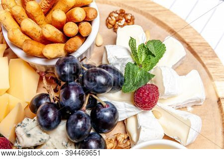 Board With Different Types Of Cheese. Cheeses Mix Set Dor Blu Chedar Parmesan Brie Honey Sauce Finge