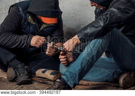 Two Shabby Men Preparing Drug Injection In Slums.