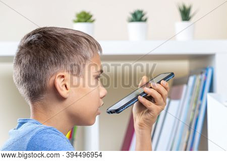 Teenage Boy Doing Homework, Using Cell Phone Recording And Send A Voice Message, Making Voice Call, 