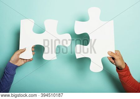 Two Peoples Join Piace Of Puzzle. Concept Teamwork, Partnership, Integration. Cyan Background