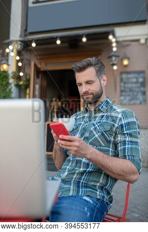 Bearded Handsome Chacking Hos Phone In Open Air Cafe
