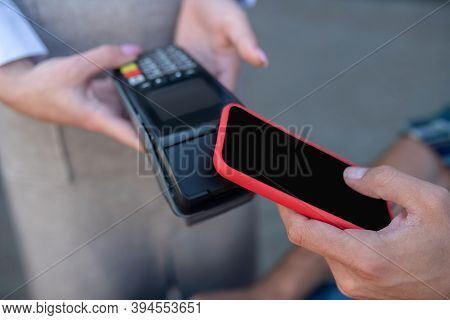 Close-up Of Male Customer Paying Bill With Smartphone