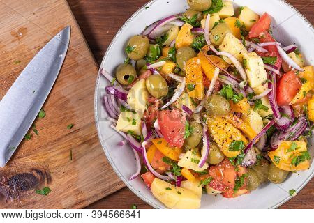 Cooking Italian Potato Calabrese Salad - A Bowl Of Boiled Potatoes, Tomatoes, Onions And Olives On A