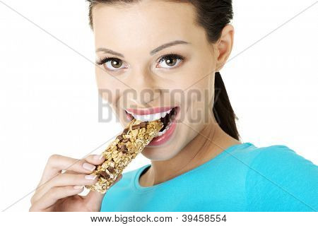 Jovem mulher comer barra de Cereal chocolate, isolada no branco