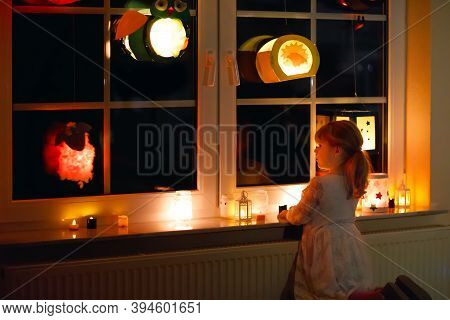 Little Kid Girl Sitting By Window With Selfmade Hand Crafted Lanterns With Candles For St. Martin Pr