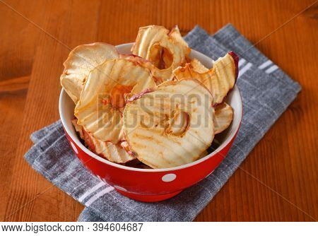 Bowl of dried apple slices - apple chips or rings - on gray napkin
