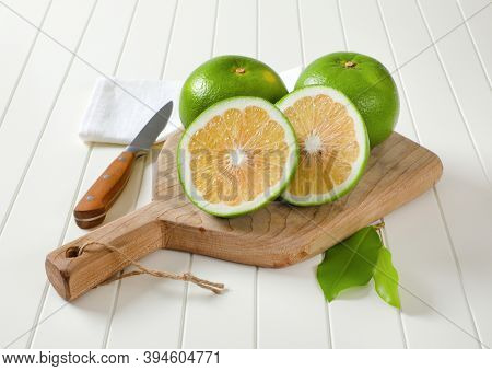 Sweetie fruits (green grapefruits, pomelits) - two whole fruits and slices - on cutting board