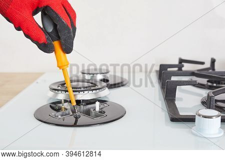 Repairs And Fixing Of Gas Control Panel. Man Hand In Protective Gloves Repairs Hotplate Of Hob.