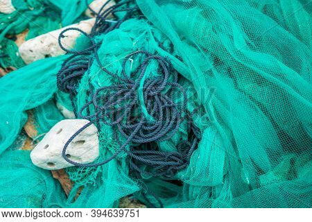 Close Up View Pile Of Green Nylon Multi Colorful Bright Fish Nets With Pieces Of White Corals And Ol