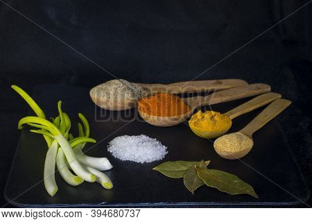 Wooden Spoons With Multicolored Spices Fragrant Seasonings Pepper Green Onion Salt And Bay Leaf