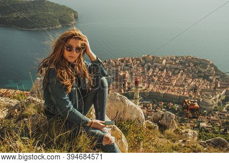 Attractive Brunette Sitting On The Srd Hill Above The City Of Dubrovnik, Observing The City In The D