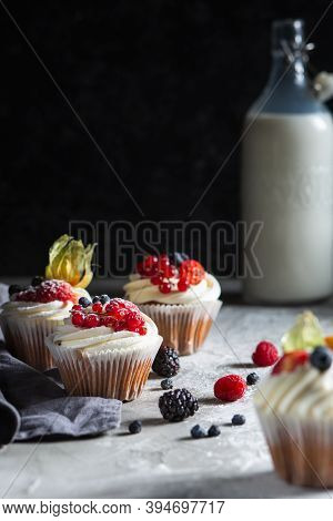 Homemade Muffin Next To A Bottle Of Milk On A Table And On A Dark Background With Fresh Berries Arou