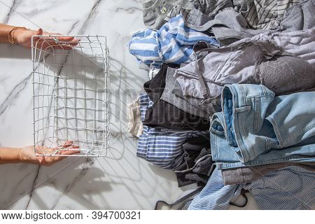 Woman Hands Putting Stack Of Clean Clothes For Neatly Tidying Up And Placing In Steel Wire Wardrobe