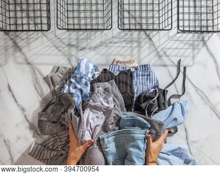 Woman Hands Putting Stack Of Clean Clothes For Neatly Tidying Up And Placing In Steel Wire Wardrobe