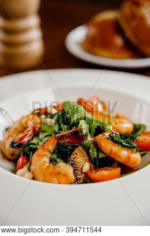 Fresh Salad Plate With Shrimp, Tomato And Mixed Greens On Wooden Background Close Up. Healthy Food.