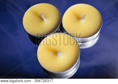 Three Yellow Candles Stand On A Blue Background.