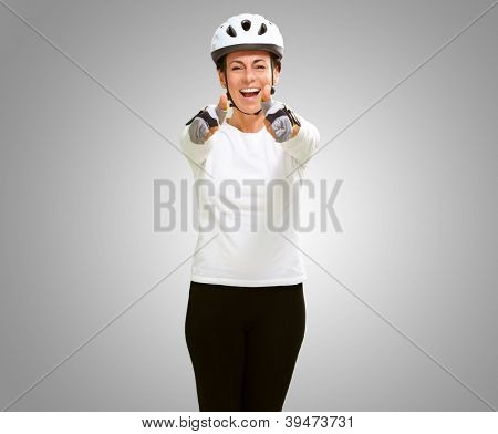 Femme portant casque montrant les deux pouces vers le haut isolé sur fond gris