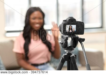 blogging, videoblog and people concept - happy smiling african american female video blogger with camera videoblogging at home