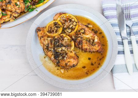 Chicken Francese - Fried Chicken Breast With Lemon Slices And Delicious Sauce On A White Plate On Th