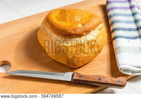 A Loaf Of Homemade Wheat Bread On A Wooden Board, A Rustic Striped Kitchen Towel And A Knife With A 