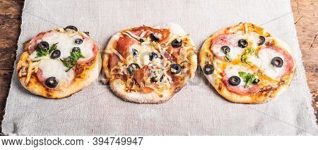 Several Ready-made Mini Pizza, Pizzetta On A Linen Napkin On A Wooden Table