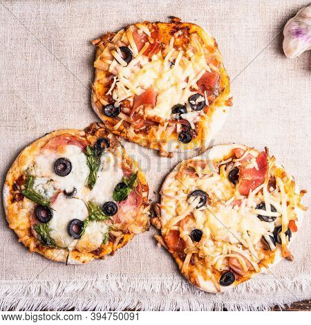 Several Ready-made Mini Pizza, Pizzetta On A Linen Napkin On A Wooden Table