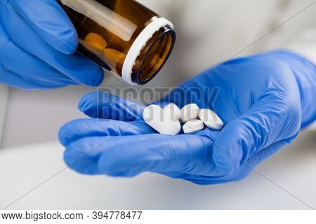 Uk Nhs Doctor,nurse,gp Medical Practitioner Wearing Blue Surgical Latex Gloves Holding Medicine Bott