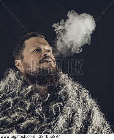 Solid Bearded Man Dressed In A Fur Mantle Exhaling Vapour