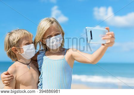 Funny Kids Taking Selfie Photo By Smartphone On Tropical Sea Beach. New Rules To Wear Cloth Face Cov