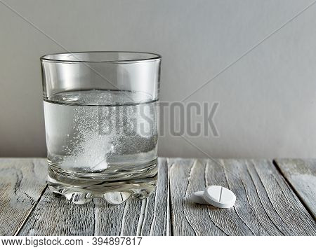 Effervescent Tablet In A Glass, Next To Two More Tablets On A Wooden Table