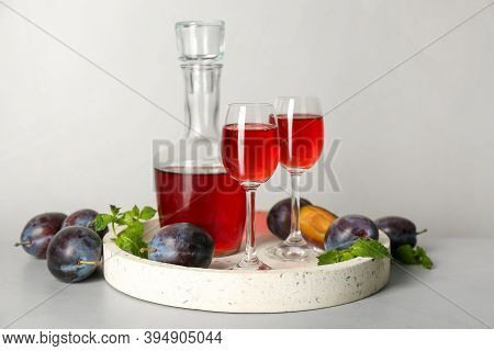 Delicious Plum Liquor, Mint And Ripe Fruits On Light Table. Homemade Strong Alcoholic Beverage