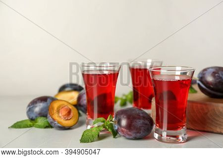 Delicious Plum Liquor, Mint And Ripe Fruits On Light Table. Homemade Strong Alcoholic Beverage