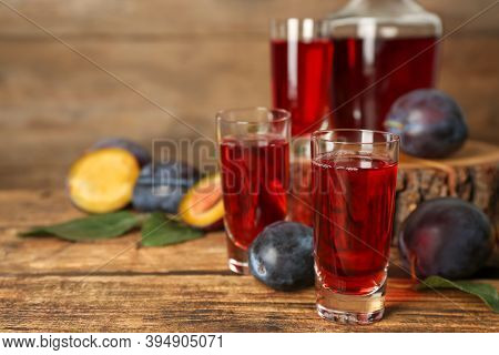 Delicious Plum Liquor And Ripe Fruits On Wooden Table. Homemade Strong Alcoholic Beverage