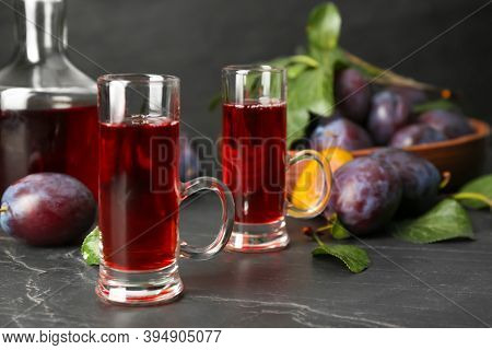 Delicious Plum Liquor And Ripe Fruits On Black Table. Homemade Strong Alcoholic Beverage