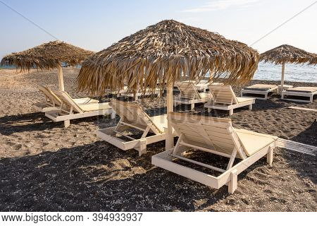 Straw Umbrella With Sun Loungers At The Vlychada Beach On The Southern Side Of Santorini, Cyclades, 