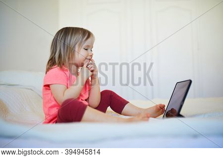 Toddler Girl With Digital Tablet At Home. Child Watching Cartoons. Kid Using Gadget To Communicate W