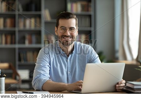 Office Employee Sitting At Desk Smiling Looking At Camera