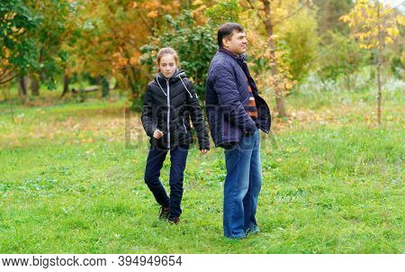father and daughter walking outdoor in autumn city park, no emotion and unhappy, walk separately, this is the problem of poor communication